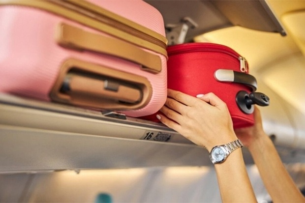 H&agrave;nh kh&aacute;ch đang cất vali x&aacute;ch tay l&ecirc;n khoang chứa đồ ph&iacute;a tr&ecirc;n m&aacute;y bay