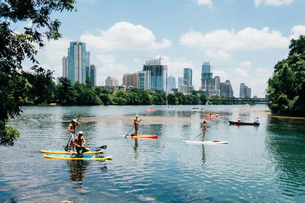 Chèo ván SUP trên hồ Lady Bird với khung cảnh trung tâm Austin phía xa Chèo ván SUP trên hồ Lady Bird với khung cảnh trung tâm Austin phía xa