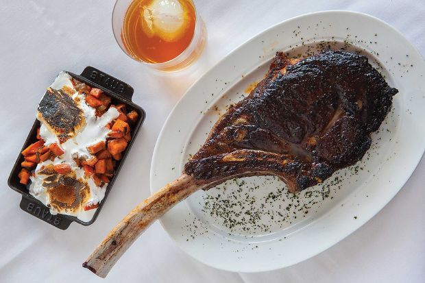 Tomahawk ribeye nướng dùng kèm khoai lang nướng trong đĩa gang nhỏ Tomahawk ribeye nướng dùng kèm khoai lang nướng trong đĩa gang nhỏ