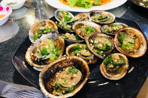 Ốc v&uacute; n&agrave;ng nướng mỡ h&agrave;nh, một loại đặc sản nổi tiếng, thường được t&igrave;m thấy ở c&aacute;c v&ugrave;ng biển C&ocirc;n Đảo