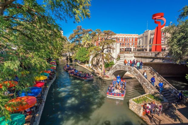 San Antonio River Walk với dòng sông uốn lượn, cầu đá và những chiếc thuyền du lịch giữa trung tâm San Antonio San Antonio River Walk với dòng sông uốn lượn, cầu đá và những chiếc thuyền du lịch giữa trung tâm San Antonio