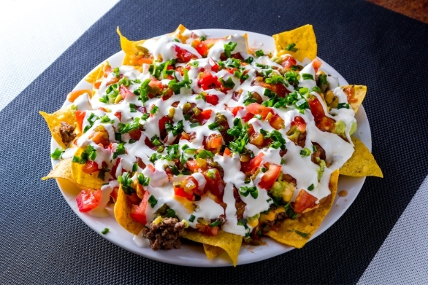 Loaded Nachos nóng hổi với lớp phô mai với thịt và sốt phủ đầy trên lớp bánh giòn rụm