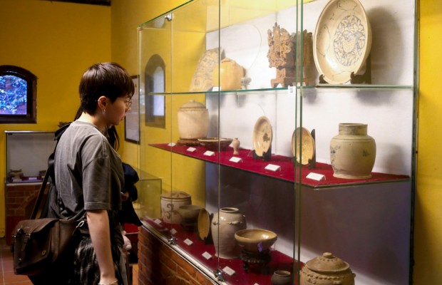 Cận cảnh c&aacute;c b&igrave;nh gốm, b&aacute;t đĩa cổ được trưng b&agrave;y dưới &aacute;nh đ&egrave;n v&agrave;ng ấm c&uacute;ng.