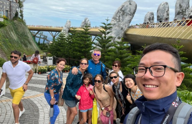 Nh&oacute;m du kh&aacute;ch mặc &aacute;o kho&aacute;c v&agrave; &aacute;o mưa nhẹ đứng check-in tại Cầu V&agrave;ng B&agrave; N&agrave; Hills