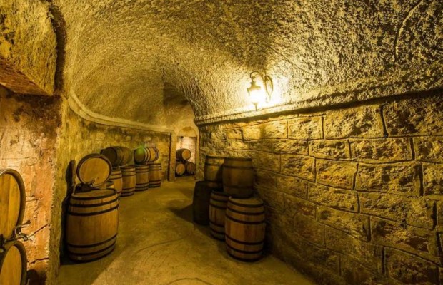 B&ecirc;n trong hầm rượu Debay B&agrave; N&agrave; Hills với c&aacute;c th&ugrave;ng gỗ xếp dọc lối đi, &aacute;nh đ&egrave;n ấm &aacute;p