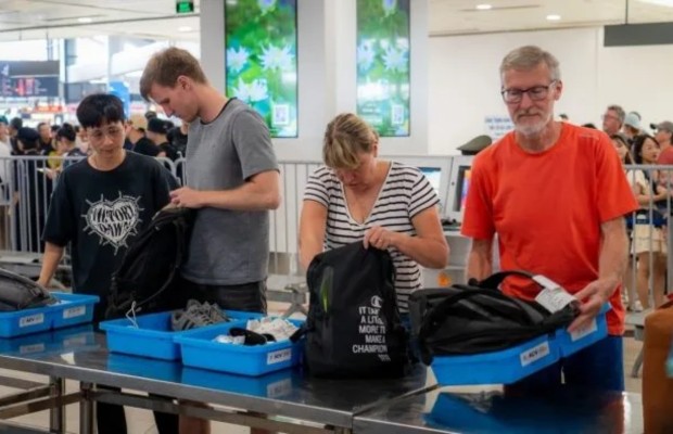 4 h&agrave;nh kh&aacute;ch đang lấy đồ từ khay nhựa sau khi qua khu vực kiểm tra an ninh tại s&acirc;n bay.