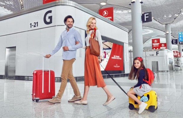 Gia đ&igrave;nh l&agrave;m thủ tục k&yacute; gửi h&agrave;nh l&yacute; tại quầy Turkish Airlines với vali đỏ v&agrave; h&agrave;nh l&yacute; x&aacute;ch tay