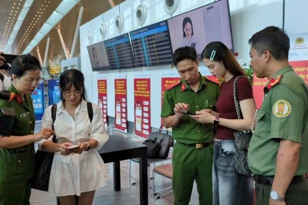 C&aacute;n bộ c&ocirc;ng an đang hướng dẫn người d&acirc;n check-in bằng nhận diện khu&ocirc;n mặt tại nh&agrave; ga T3 T&acirc;n Sơn Nhất