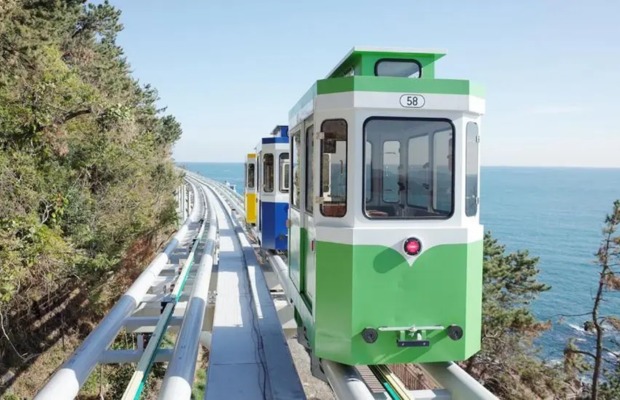 Toa t&agrave;u Sky Capsule nhiều m&agrave;u sắc chạy dọc đường bờ biển Busan xanh ngắt.